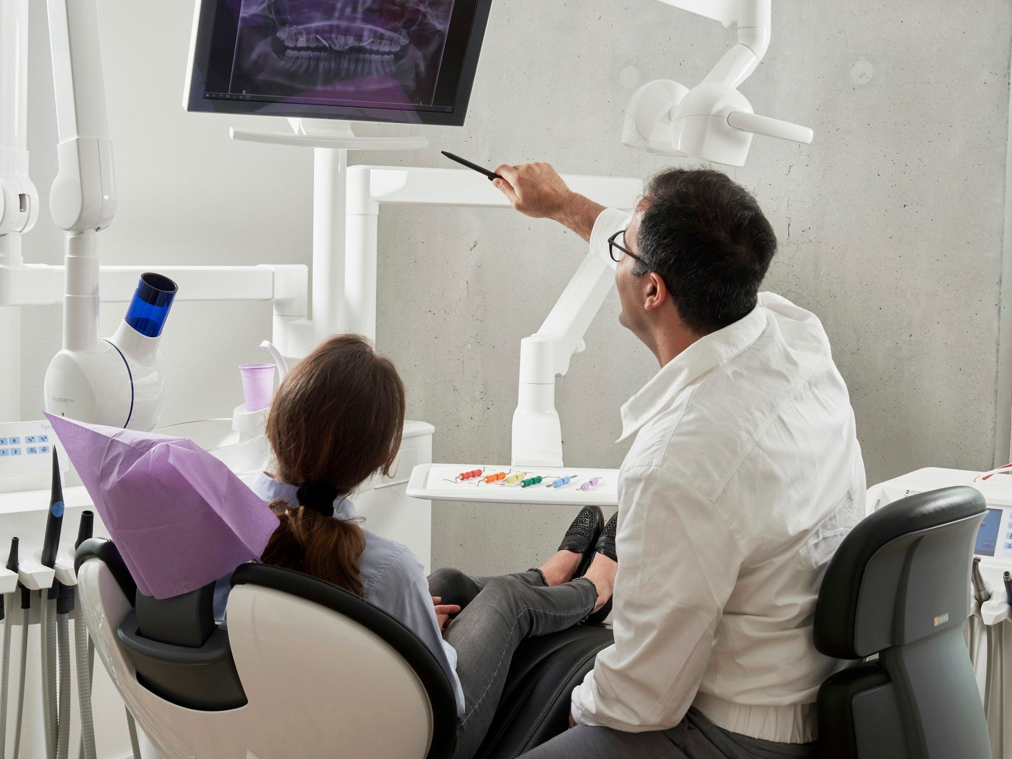 Dentist explaining a panoramic X-ray to a patient in a treatment room